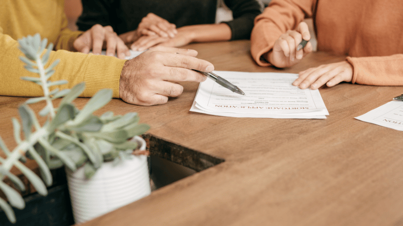 A mortgage advisor explains the terms of a further advance on a mortgage application to a couple, representing the process of securing additional borrowing on a mortgage.